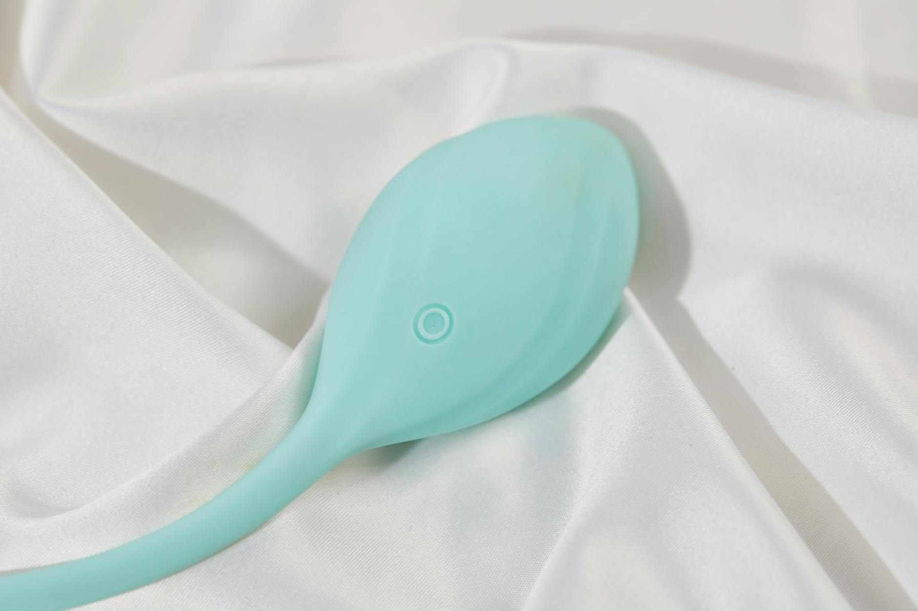 A stylish vibrator on smooth white silk fabric, promoting self-love and sexuality.