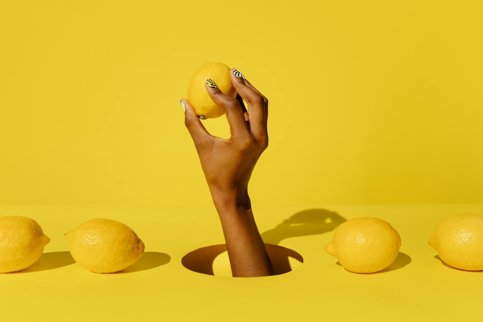 Hand holding a fresh lemon against a vivid yellow background, symbolizing renewal and refreshed sensation