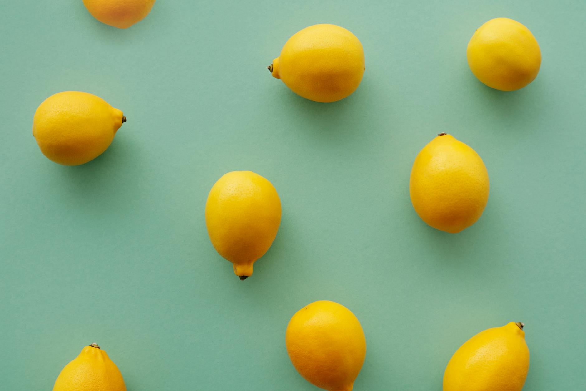 Bright yellow lemons on a pastel green background symbolizing revival and fresh sensation
