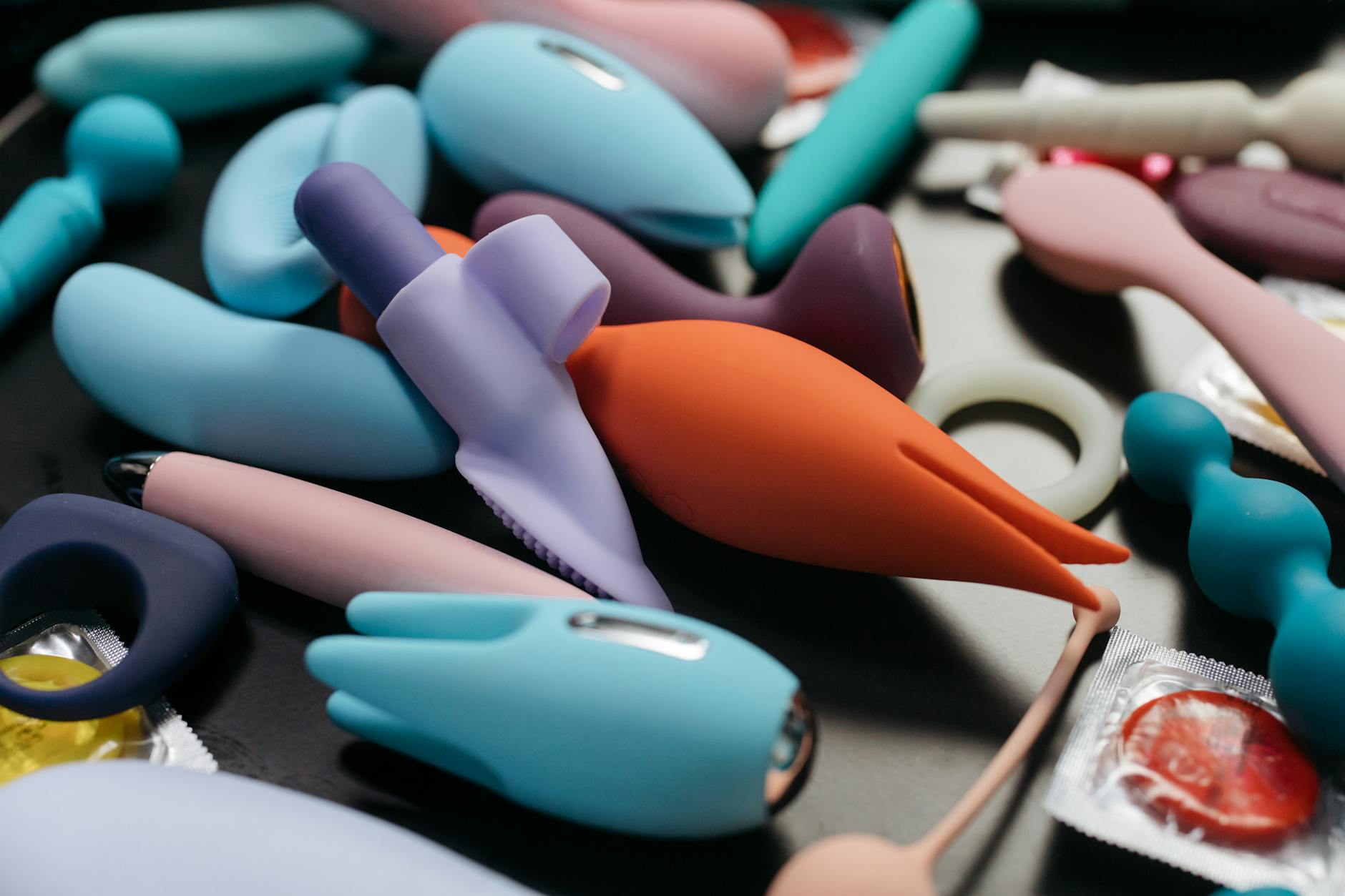 Close-up of hands holding a sleek blue vibrator against a purple background, representing intimacy between partners