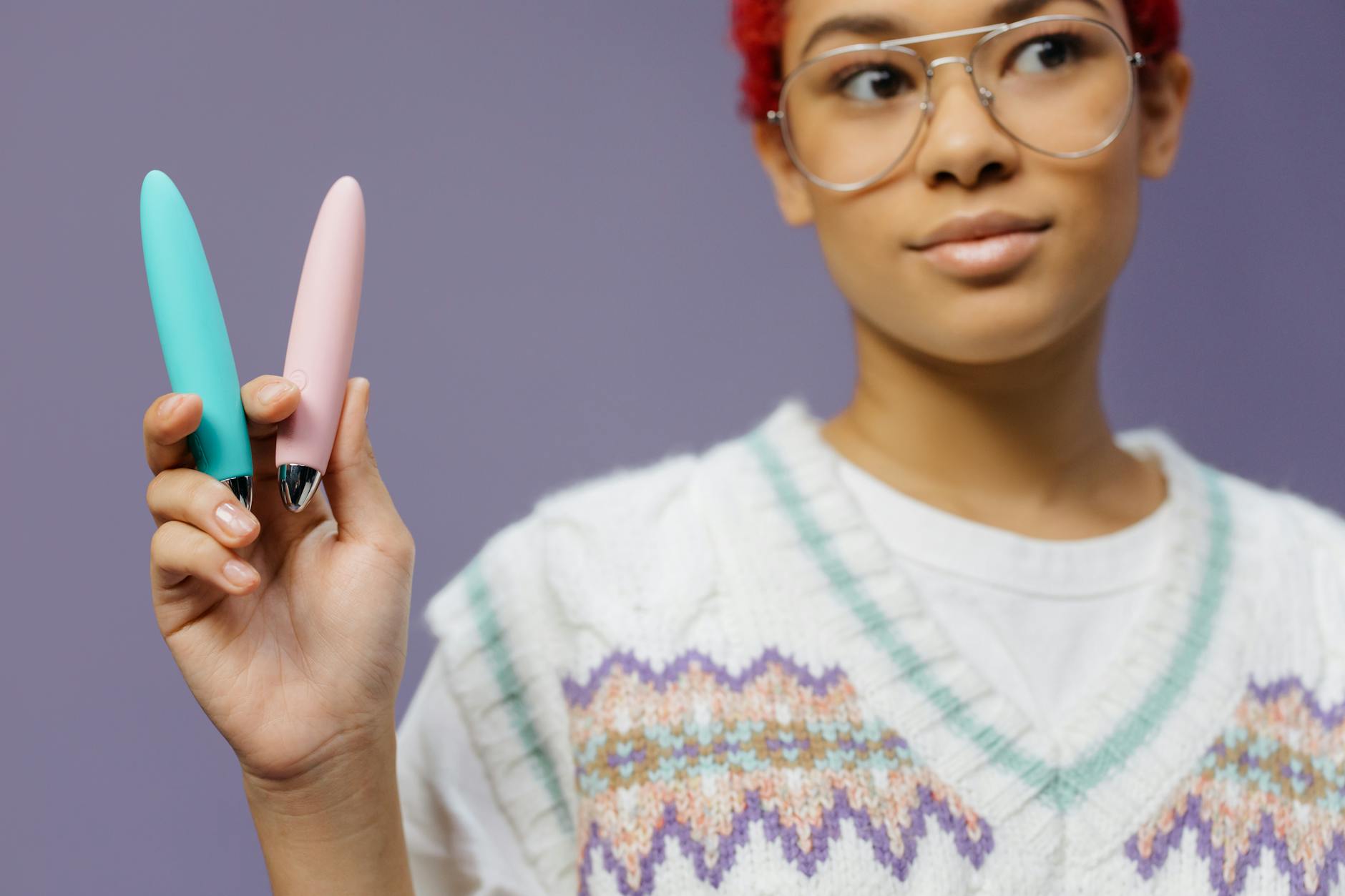 A blue silicone sex toy held in hand against a purple background, symbolizing self-directed pleasure and healing