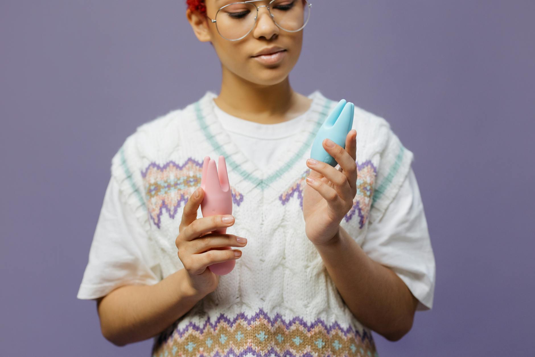 Woman holding clitoral vibrators, considering which one to try first
