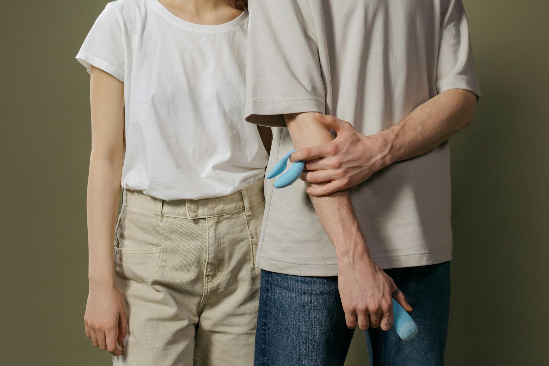 A couple holding a blue vibrator together, representing modern intimacy after hormonal changes