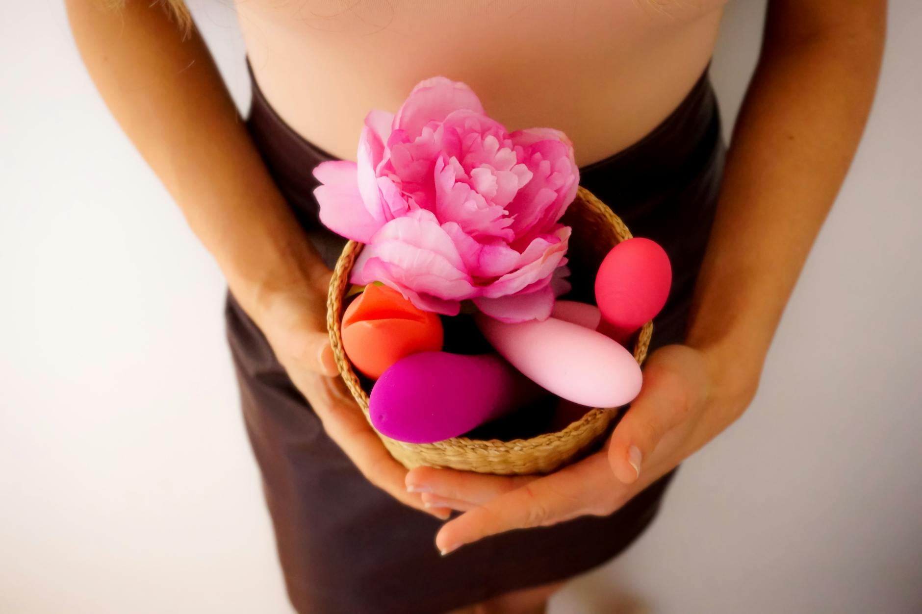 Vibrant collection of modern clitoral vibrators in a woven basket with fresh flowers